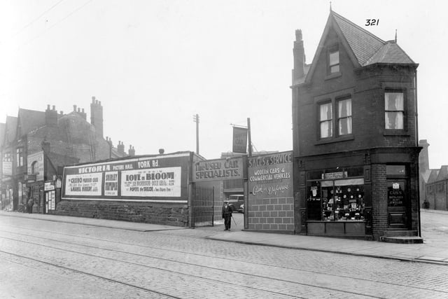York Road in September 1935. On the left, property belonging to Thomas Cropper, tobacconist. He is listed at numbers 152 and 346, the shop premises do appear to occupy different buildings. In the centre, forefront of yard, 'Universal Car Exchange' number 142. A poster for Victoria Picture Hall is visible, with a programme which includes Laurel and Hardy, Shirley Temple and Popeye. The corner shop is business of William Cuss, watchmaker and jeweller. The road on the right is Berking Avenue.