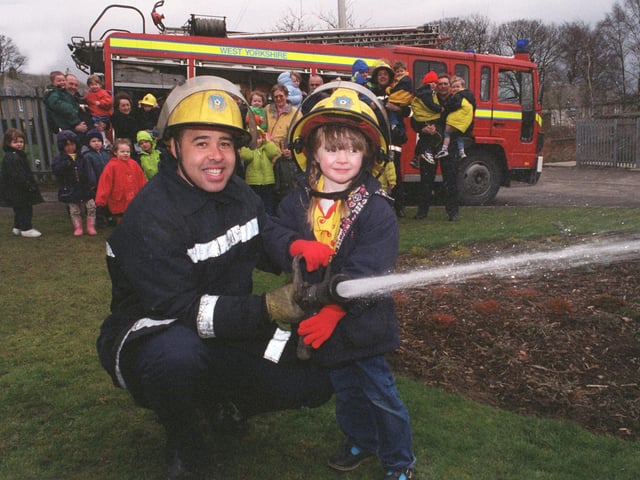Fire crews from Cookridge Fire Station visited Iveson Primary School to talk to pupils about the dangers of fire in February 1999. Firefighter Stephen Ebanks shows pupil Grace Oliver how to use a hose .