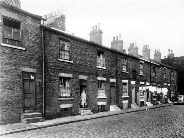 A lady stands in the doorway of a house on Orchard Way in October 1958. Above the door of the house next door is a plaque. This plaque appears to be too large for a datestone and may be connected to the former South Accommodation Congregational Church which these houses faced onto.