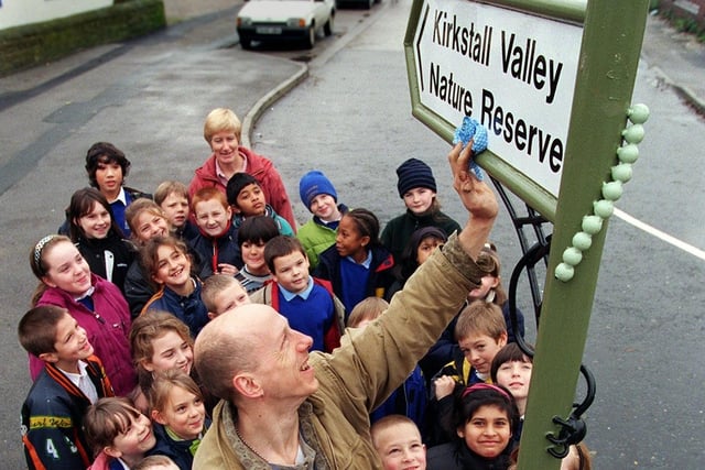 Sculptor Mick Kirkby Geddes puts the finishing touches to a new road sign to Kirkstall Valley Nature Reserve in November 1998 watched by children from Burley St. Matthias School who helped create it.
