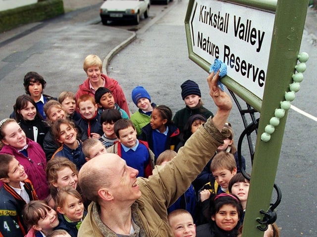 Sculptor Mick Kirkby Geddes puts the finishing touches to a new road sign to Kirkstall Valley Nature Reserve in November 1998 watched by children from Burley St. Matthias School who helped create it.