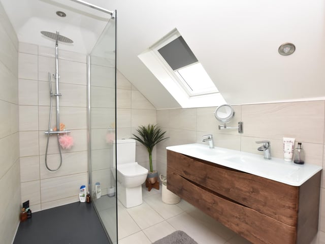 The bathroom has a three-piece suite in white which incorporates electric shower facilities over the bath, ceramic tiled walls, cast iron radiator and window to the side.