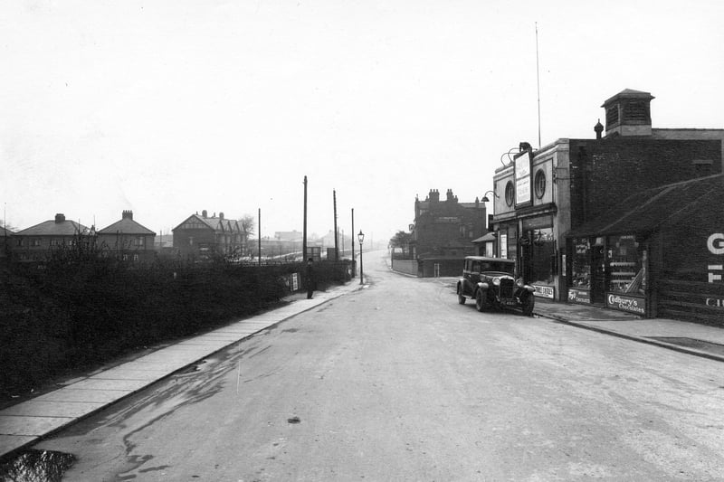 Looking north along Station Road towards the bridge crossing the railway line. On the right is a confectioners then the Crossgates Picture House Cinema, which opened on  August 5, 1920 and closed on May 16, 1965. Next to this is the entrance to the railway station and beyond the bridge the Station Hotel. On the far left are houses on Cold Well Road.