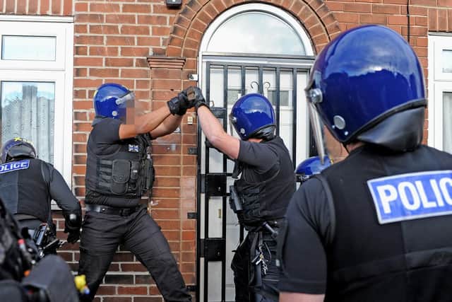 Officers from the operational support team start to force open the grille over the entrance door.