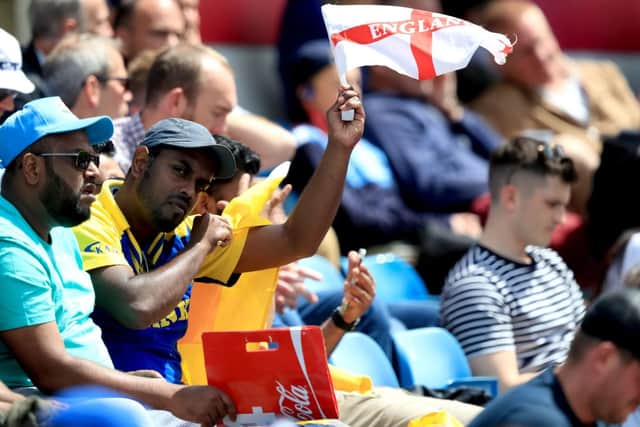 A Sri Lanka fan in the stands waves an England flag.
