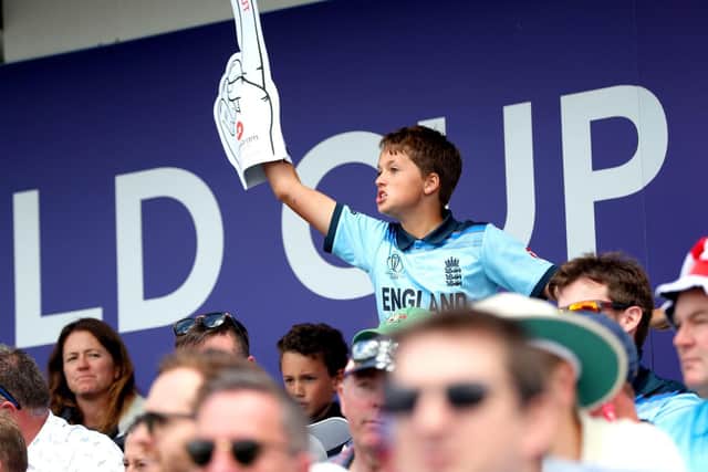 An England fan in the stands with a foam finger.