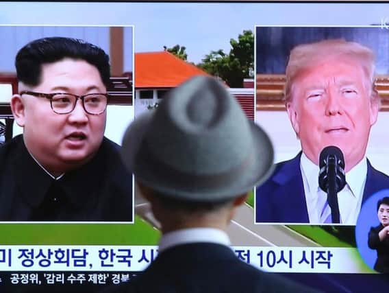 A man watches a TV screen showing file footage of U.S. President Donald Trump, right, and North Korean leader Kim Jong Un during a news program at the Seoul Railway Station in Seoul, South Korea, Monday, June 11, 2018. Final preparations are underway in Singapore for Tuesday's historic summit between President Trump and North Korean leader Kim, including a plan for the leaders to kick things off by meeting with only their translators present, a U.S. official said. The signs read: " Summit between the United States and North Korea." (AP Photo/Ahn Young-joon)