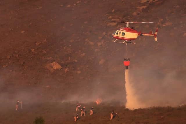 A helicopter drops water as firefighters tackle the fire. PA