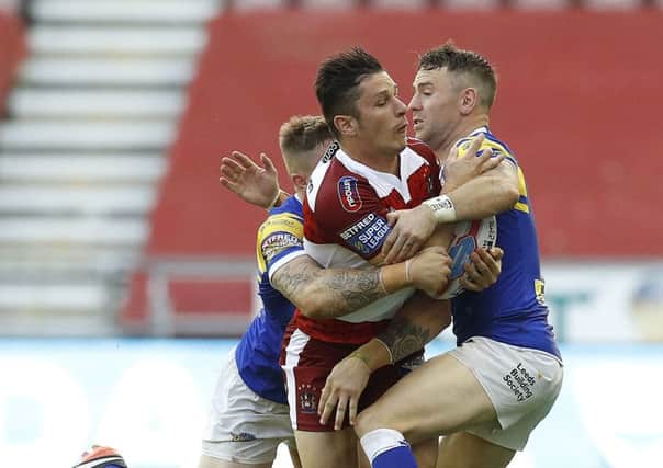 Wigan Warriors' Morgan Escare is tackled by Leeds Rhinos' Liam Sutcliffe (left) and Richie Myler (right).