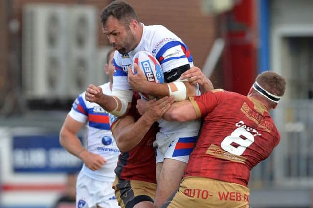 Anthony England is held by Remi Casty.
 He damaged a biceps late in the game but could be fit to face Leeds Rhinos.