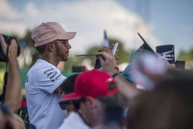Mercedes driver Lewis Hamilton signs autographs for fans on the Hungaroring circuit. (Zoltan Balogh/AP)