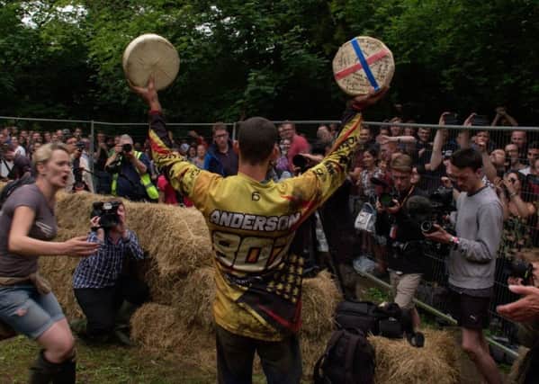 WHEELS OF FORTUNE: Double Double Gloucester winner Chris Anderson celebrates with his prizes at the bottom of Coopers Hill after hurtling to victory in the cheese-rolling competition.