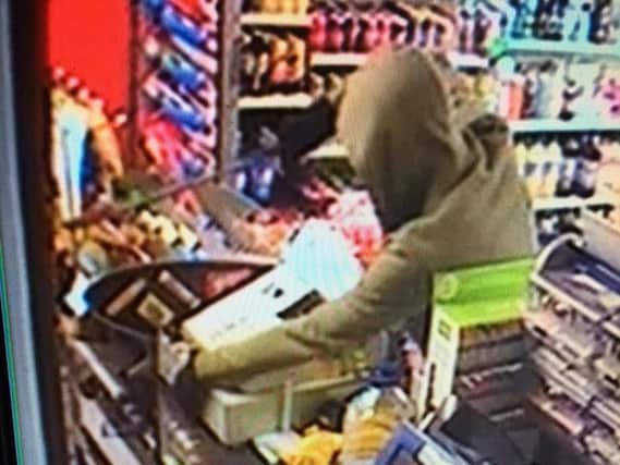 The robber with the 18" blade threatens the shopkeeper.