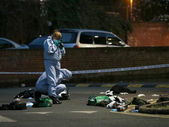 Forensics officers inspect the area outside Landor House, Camberwell, London, after four people were taken to hospital with stab wounds. Five males have been arrested. PIC: Jonathan Brady/PA Wire
