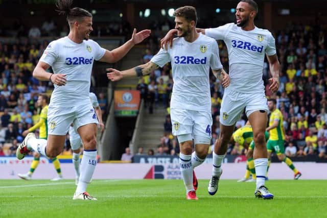 Kalvin Phillips and Kemar Roofe celebrate with Mateusz Klich after his opening goal at Carrow Road.