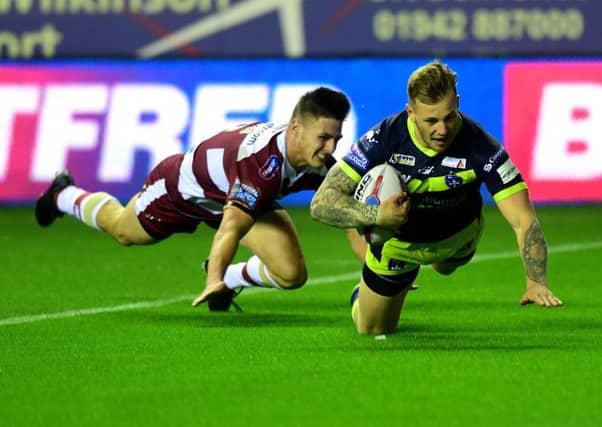 Wakefield's Tom Johnstone beats Wigan's Thomas Davies to score his side's opening try.