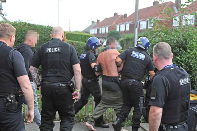 One of the suspected spice dealers arrested in the latest raids is led away by police. Picture: Tony Johnson