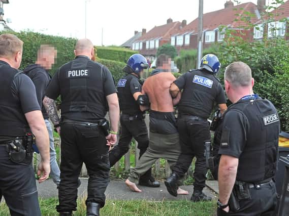 One of the suspected spice dealers arrested in the latest raids is led away by police. Picture: Tony Johnson