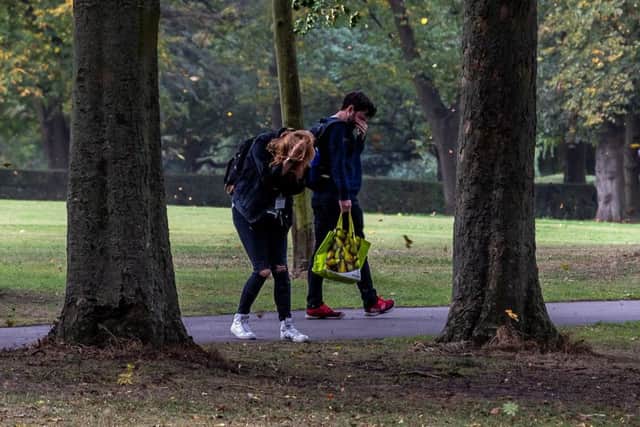 BLUSTERY: A couple walking through Woodhouse Moor cover their eyes as debris is blown in the air. PIC: James Hardisty