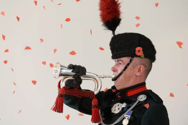 Sergeant Craig Rosser plays the last post as poppies fall. at Armistice Day service at the Royal Armouries, Leeds, in November 2017