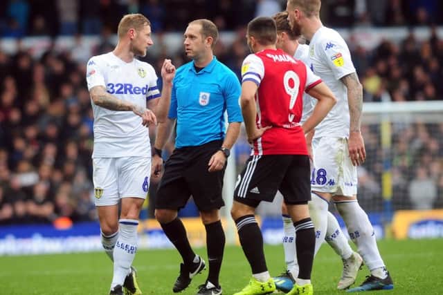 Players suround referee Jeremy Simpson.