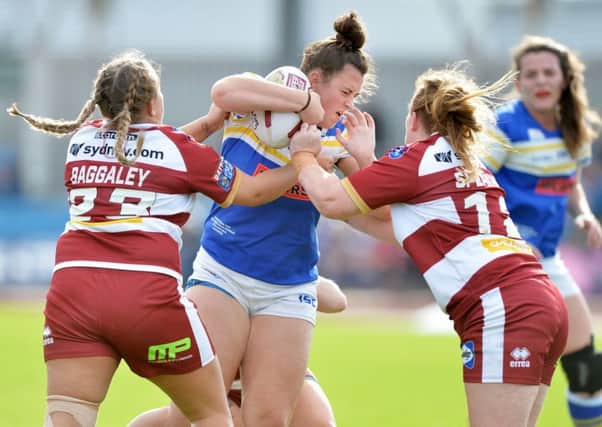 Leeds Rhinos' Shannon Lacey is held by Lucy Baggaley and Holly Speakman from Wigan.