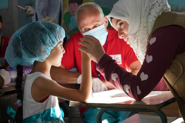 Graham Temple treating a young girl. Photo by Naoki Takyo for the Syrian American Medical Society.