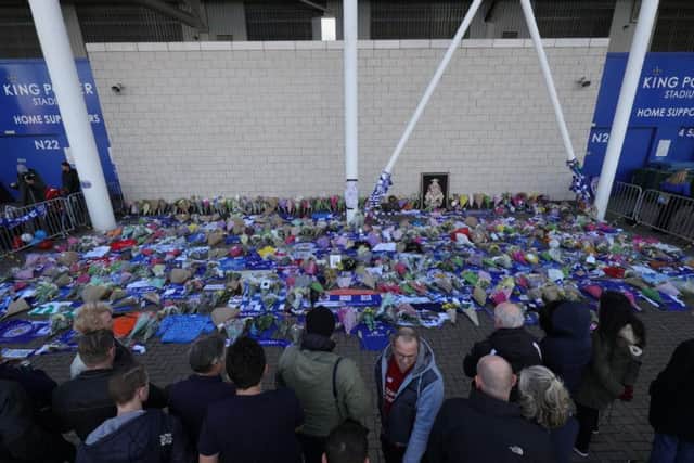Supporters pay tribute at Leicester City Footbal Club following a helicopter used by club owner Vichai Srivaddhanaprabha, crashing into flames in a car park near the stadium shortly after 8.30pm on Saturday evening. Aaron Chown/PA Wire