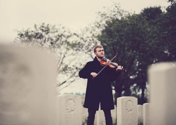 Sam Sweeney plays the violin next to Richard Howard's grave at Ypres in Belgium.