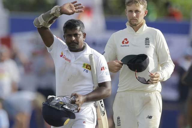 England's captain Joe Root, right, watches as Sri Lanka's Rangana Herath who played his career last test match waves after Sri Lanka lost to England by 211 runs.