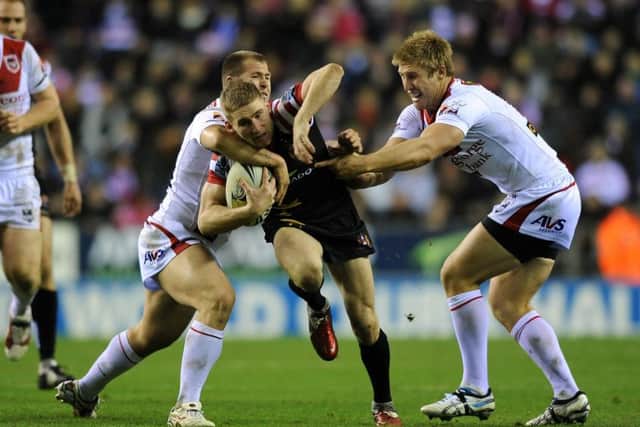 Wigan Warriors' Sam Tomkins is tackled by St George Illawarra Dragons' Michael Greenfield and Trent Merrin.