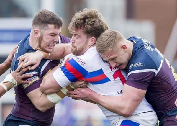 Wakefield's Danny Kirmond is tackled by Cameron Smith, left.