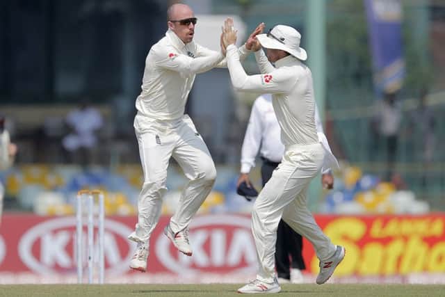 England's Jack Leach, left, celebrates taking the wicket of Sri Lanka's Lakshan Sandakan in Colombo. Picture: AP/Eranga Jayawardena.
