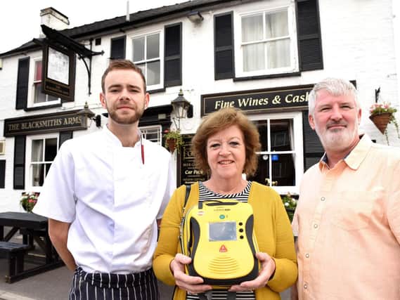 Chef James Priest (left) ran for the village defibrillator which parish councillor Anne Clark (centre), who happened to be cycling past, unlocked. PIC: SWNS