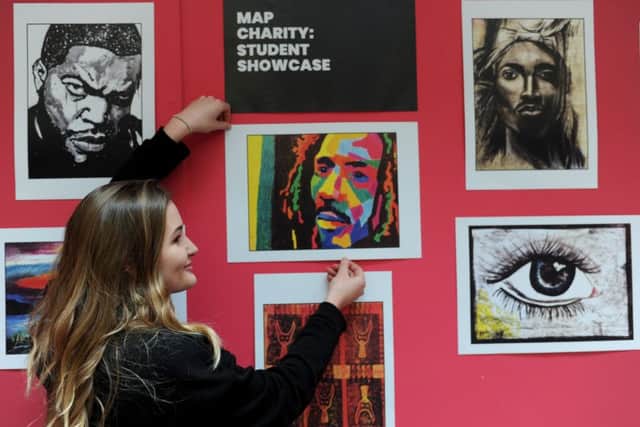 Former student Taylor Hogan puts up work by MAP student. Picture: Gerard Binks Photography