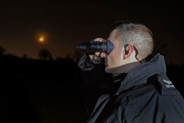 PC Andy Katkowski scans the fields using night vision binoculars.