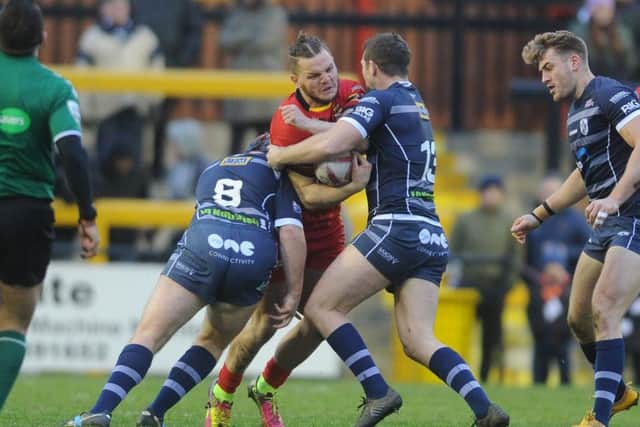 Dewsbury's Kyle Trout crashes into Featherstone's Luke Cooper and James Lockwood.