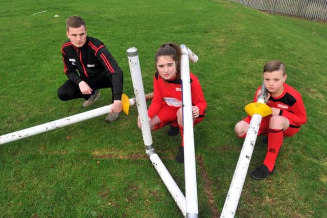Sports teacher Callum Postle and 10-year-old pupils Millie and Ryan with the damaged set of goalposts.