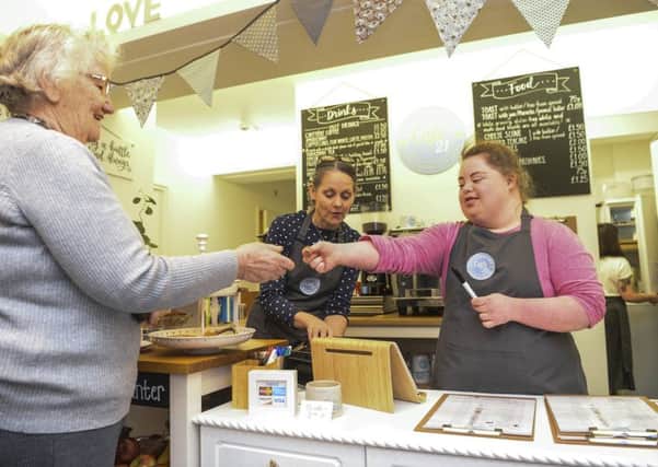 Smiles: Katherine ODonnell, 21 who has Downs syndrome serving a customer at 21 Co Cafe in Headingley, Leeds.
