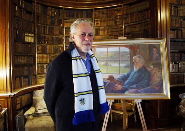 David Lascelles, the 8th Earl of Harewood, proudly wears a Leeds United scarf as he stands in front of a portrait of his late father.