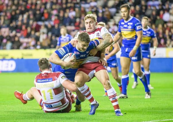 Stevie Ward is tackled by Joe Greenwood and Sam Powell of Wigan Warriors.