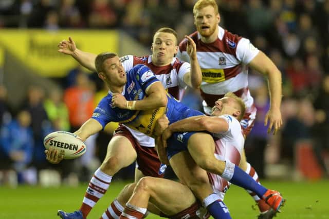 Jack Walker looks for the pass as he is held by the Wigan defence.