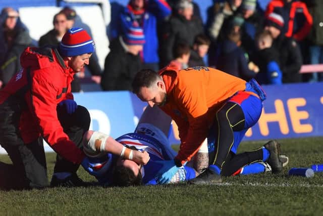 Wakefield Trinity's Craig Huby receives treatment for a shoulder injury against St Helens.