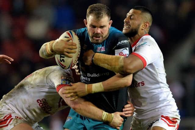 Leeds Rhinos' Adam Cuthbertson is held by Luke Thompson and Dom Peyroux of St Helens.