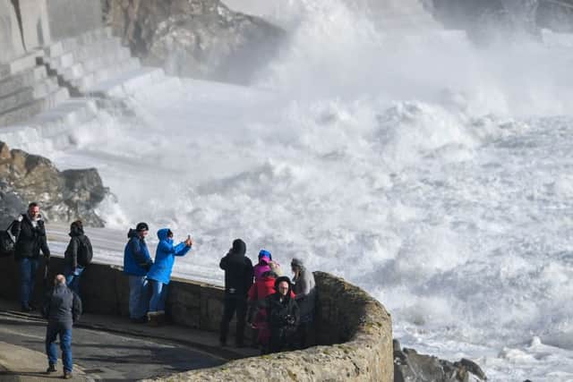 People photograph the waves battering the coast at Porthleven, Cornwall. PIC: PA
