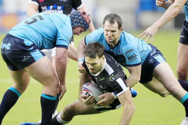 Widnes' Jay Chapelhow tackled by Featherstone's Luke Cooper and James Lockwood.