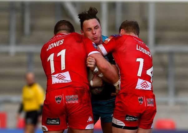 James Donaldson, is tackled by Salford's Josh Jones and Joey Lussick.