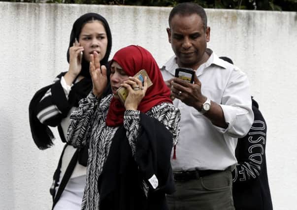 People wait outside a mosque in Christchurch waiting for news about loved ones caught up in two mass killings.