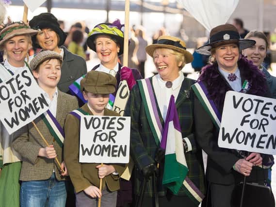 Participants dressed in suffragette period costume take part in CARE International's Walk in Her Shoes march in central London, to mark International Women's Day.