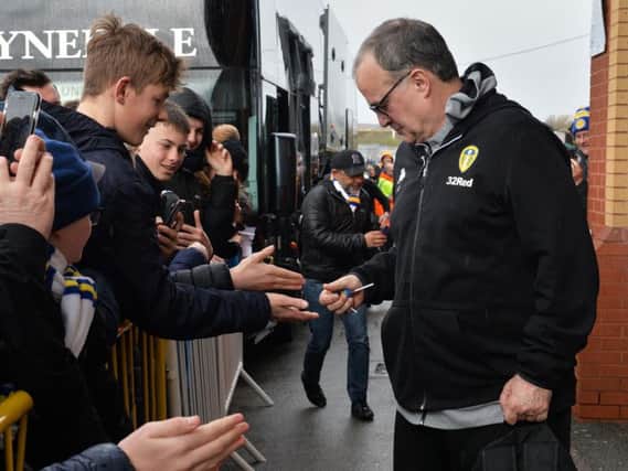 Leeds United head coach Marcelo Bielsa hands out sweets to supporters.